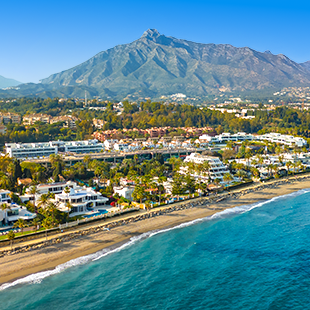 Uitzicht op de kust van de Costa del Sol met turquoise zee, rotsachtige kliffen en groen begroeide heuvels langs de zonnige Spaanse kust.